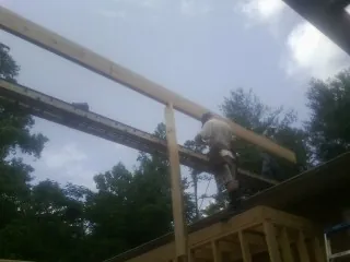 Carpenter setting a ridge beam over a new addition frame — Ice Dam Removal by Roofing Brothers in Apex