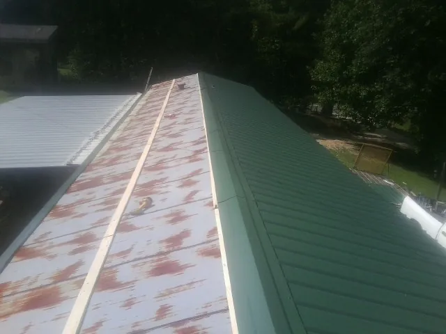 Old rusted panels beside newly installed green metal roofing — Wind Damage Roof Repair by Roofing Brothers in Apex