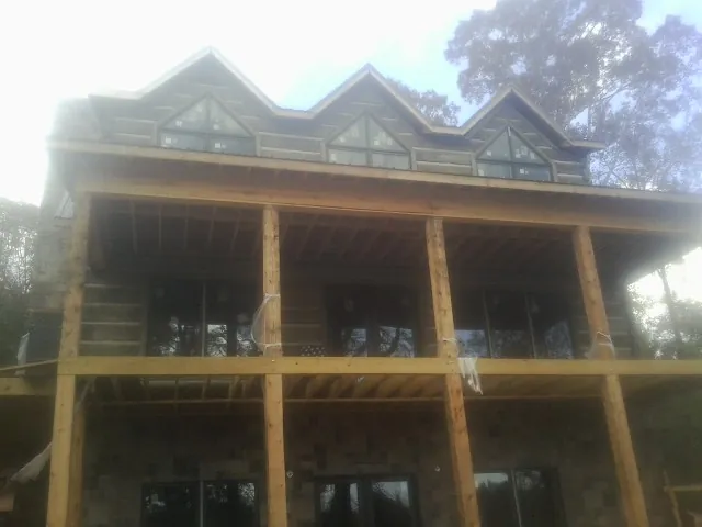 Dormers and porch framing on a large log home under construction — Roof Coating work by our crew in Apex
