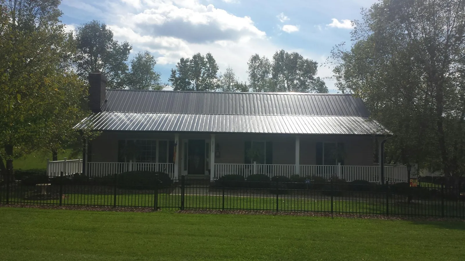 Gray metal roof on a brick ranch with a full width front porch — Gutter Guard Installation work by our crew in Apex