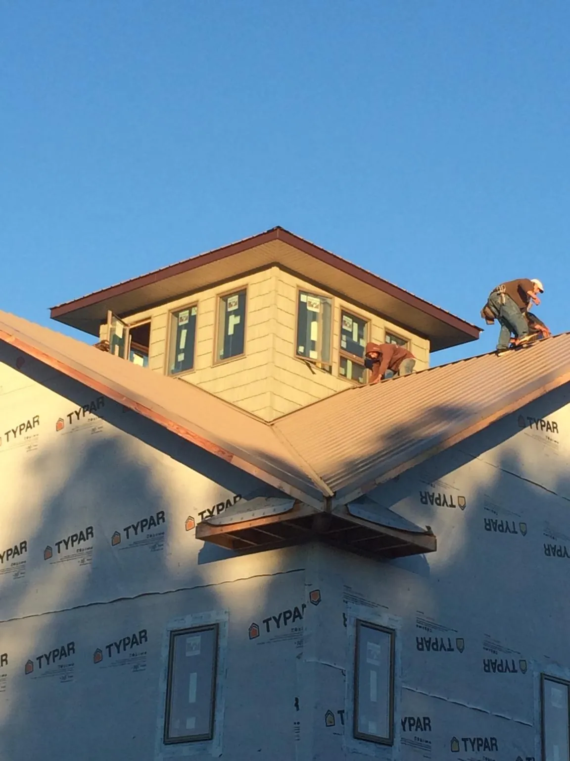 Roofers working around a rooftop cupola on a new metal roof at sunset — Roof Waterproofing in Apex by Roofing Brothers